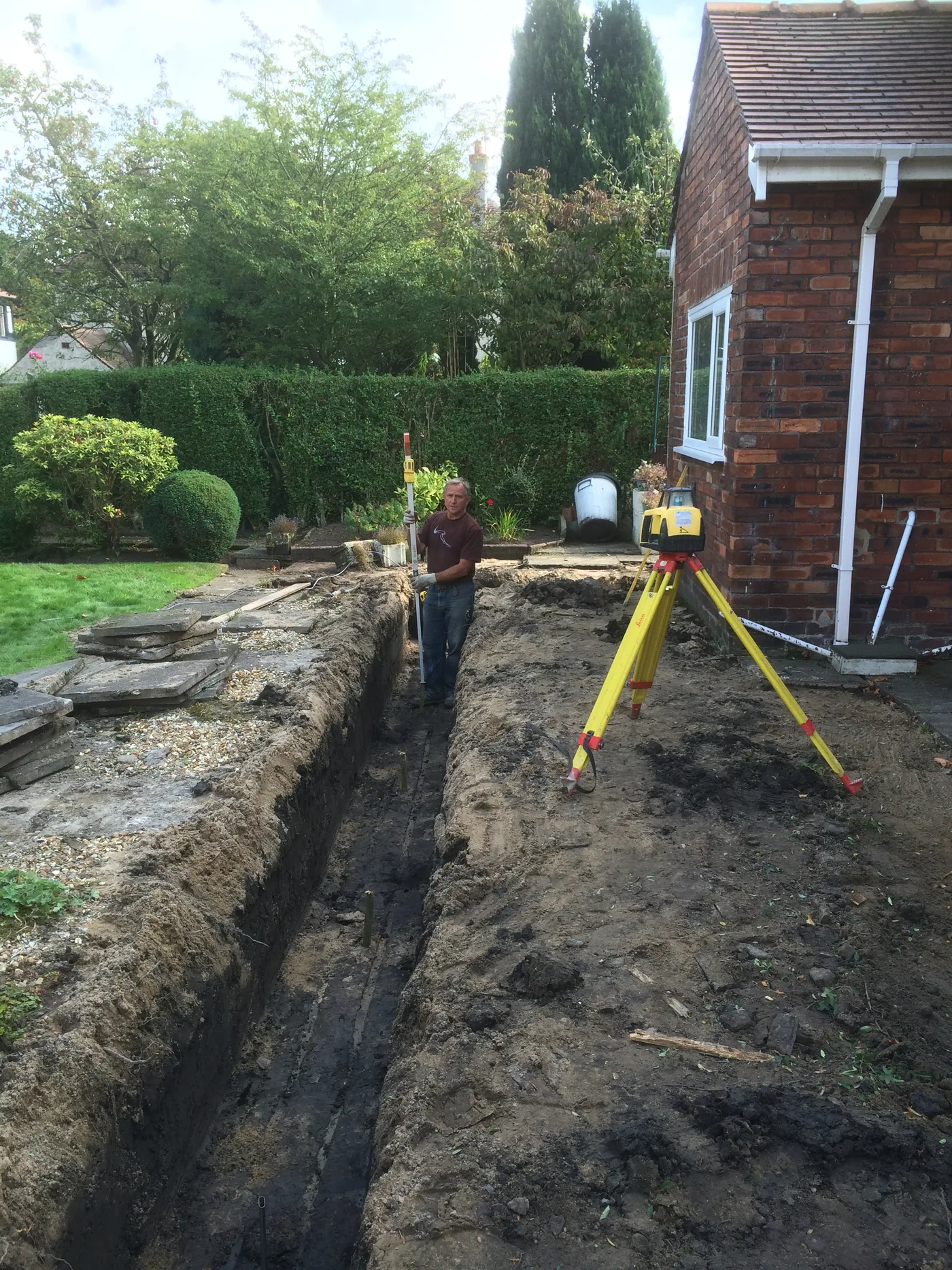 New drainage runs excavated and set to level using a laser level on a tripod.