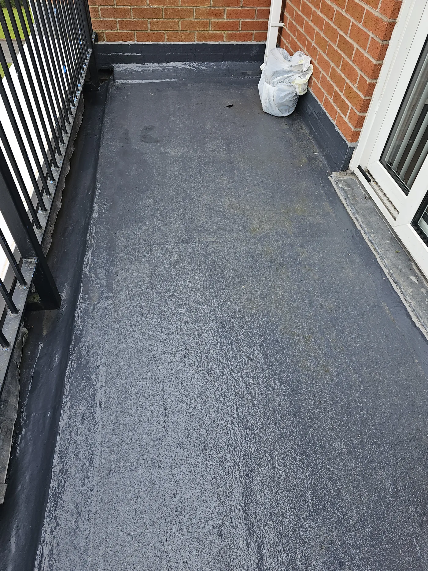Completed mastic asphalt balcony deck laid up to the threshold with a metal balustrade.