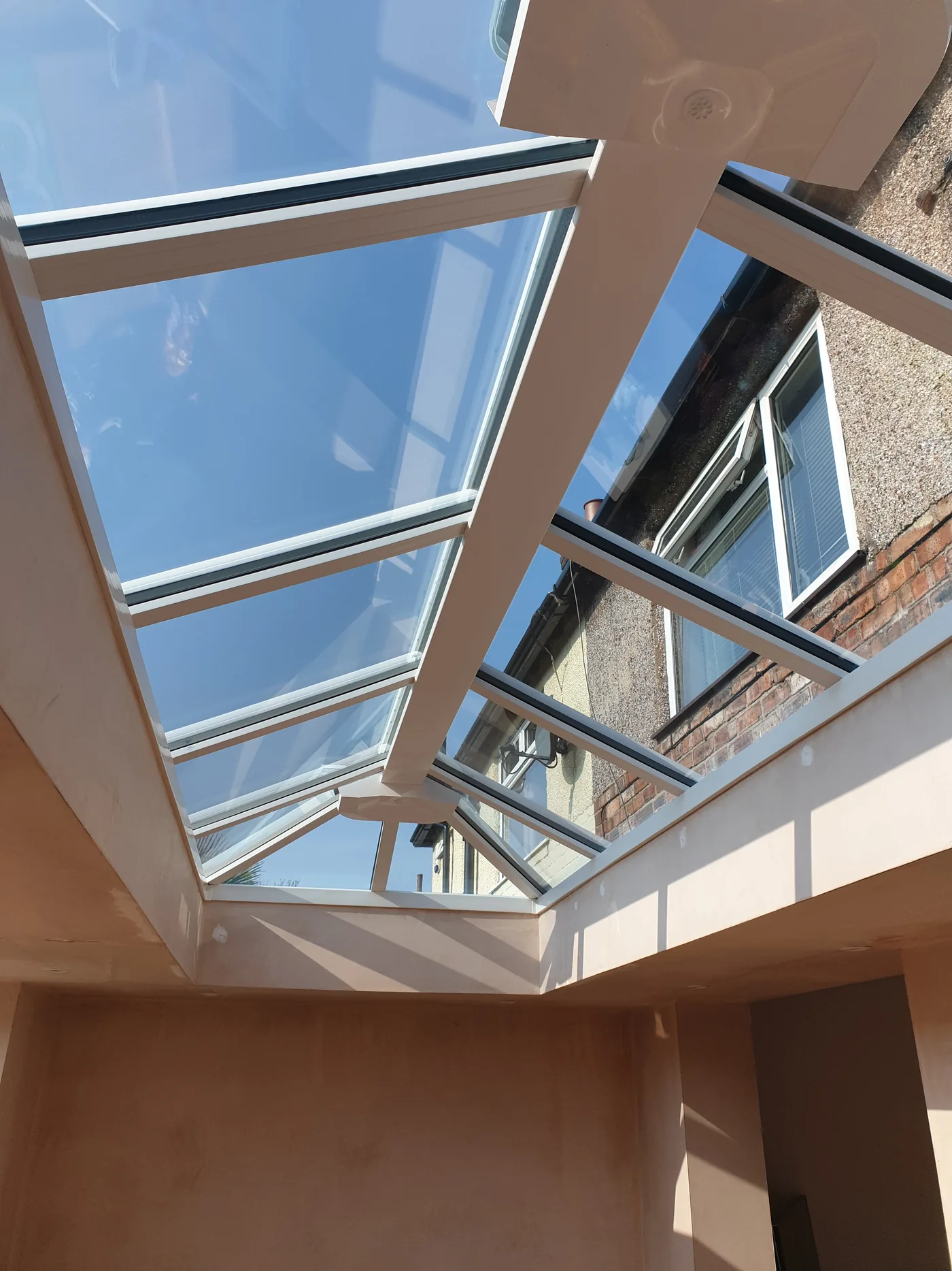 A roof lantern seen from below against blue sky, framed into a new flat roof.
