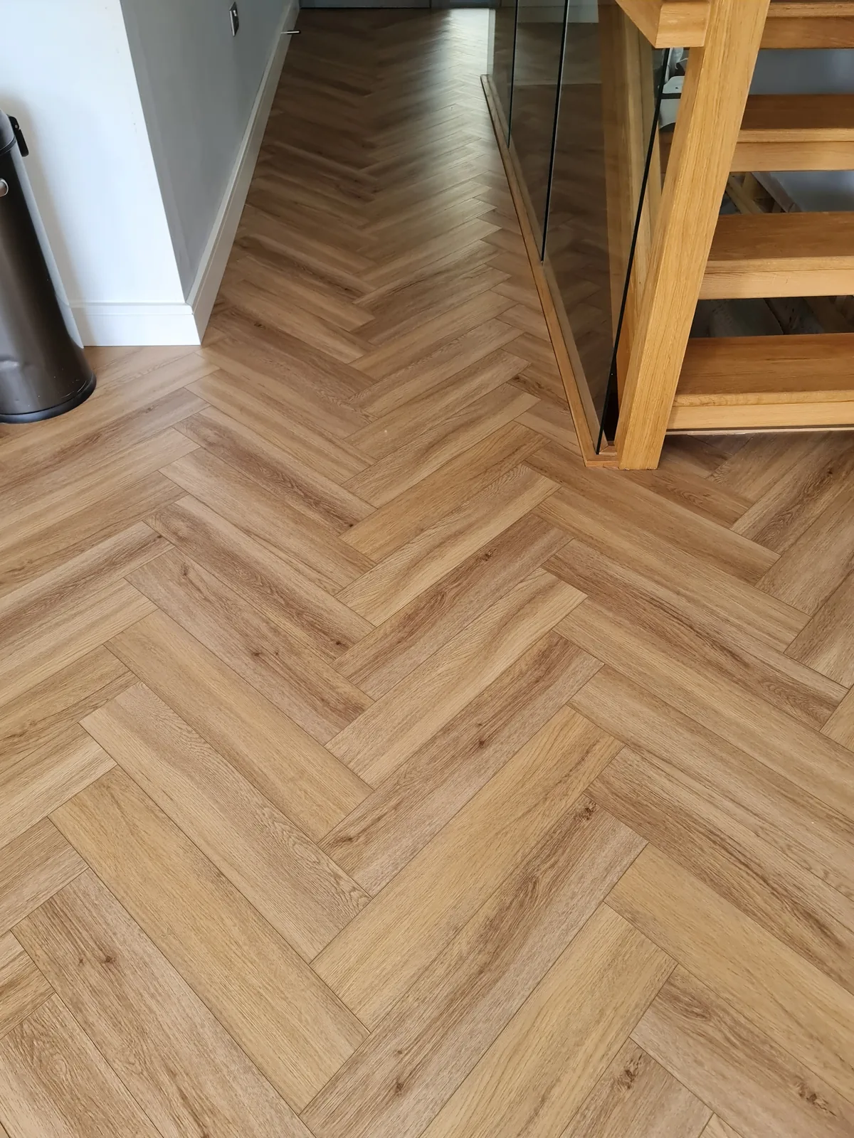 Close-up of herringbone engineered wood flooring laid up to a staircase.