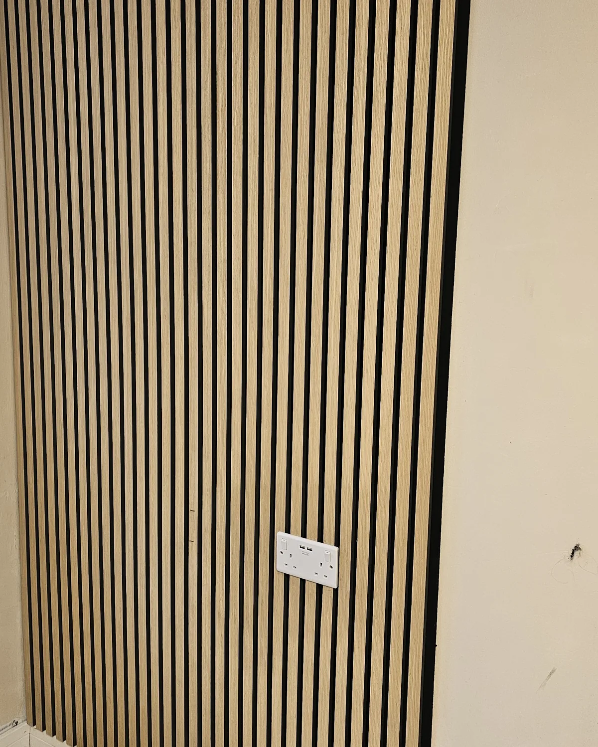 Full-height oak slatted feature wall in a hallway.