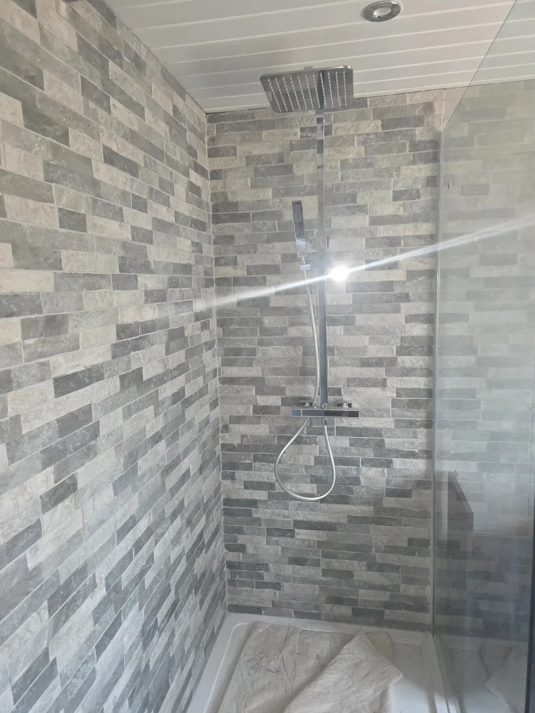 Tiled shower area with a concealed valve and large-format wall tiling.