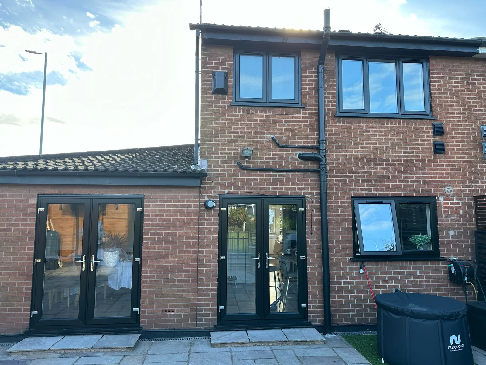 Rear elevation of a completed extension with two sets of anthracite French doors and new porcelain paving.