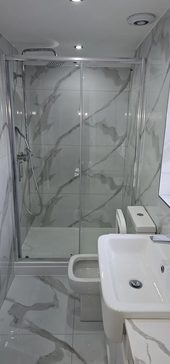 Completed walk-in shower with marble-effect porcelain, glass screen and low-profile tray.
