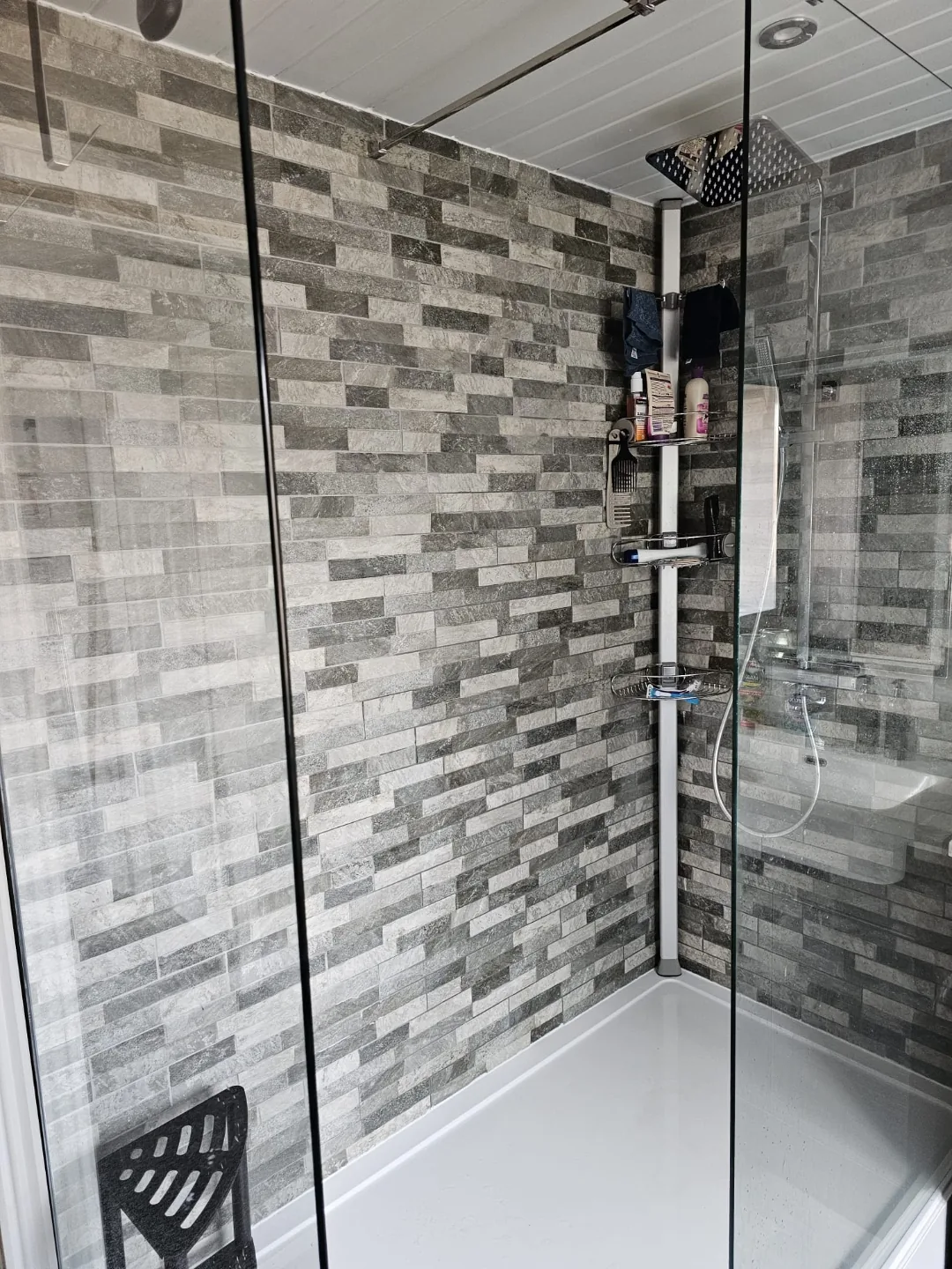 Fully tiled shower enclosure with recessed niche and glass screen.