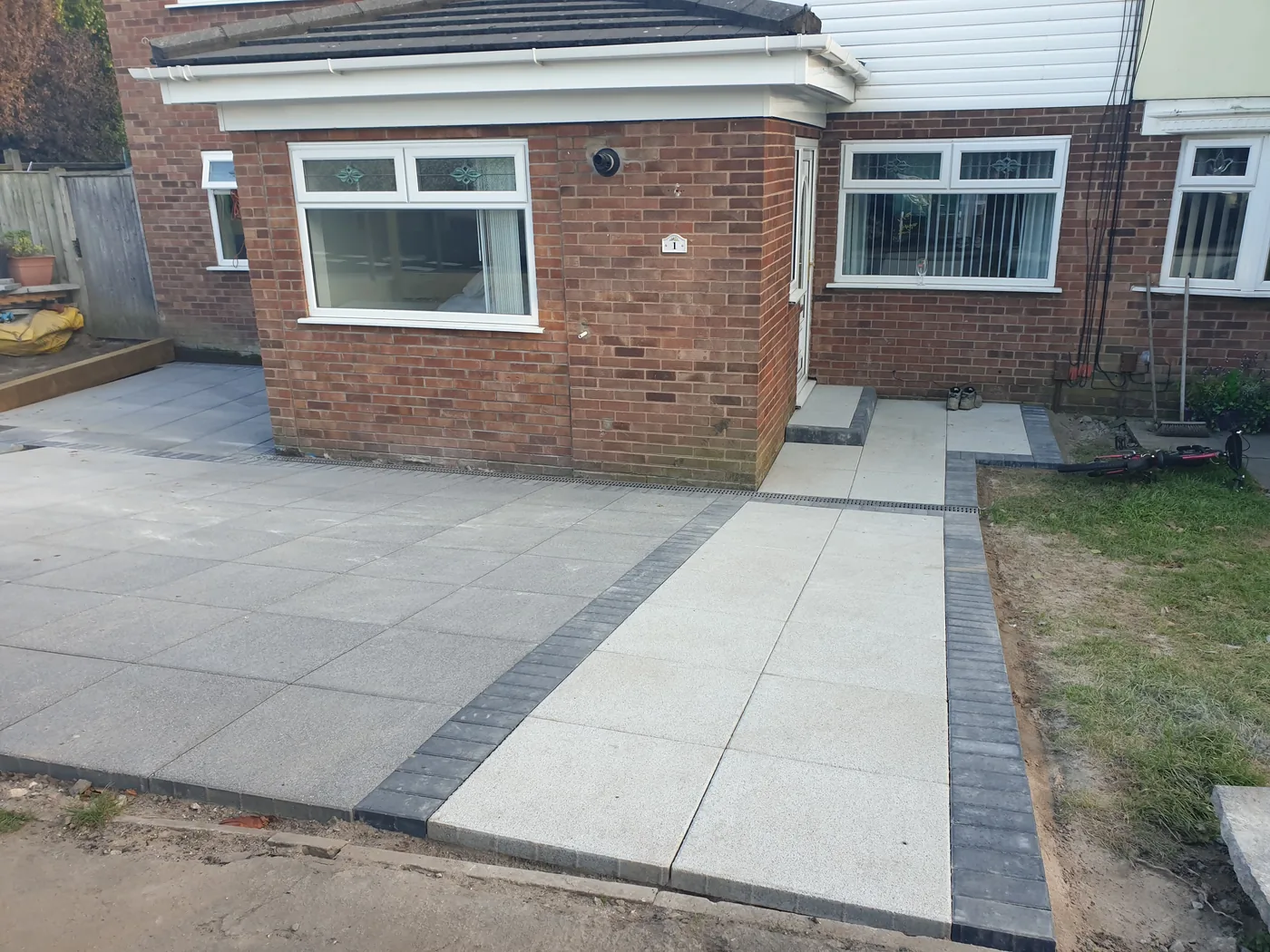 Completed single-storey side extension in matched brickwork with new paving and a block-edged path.