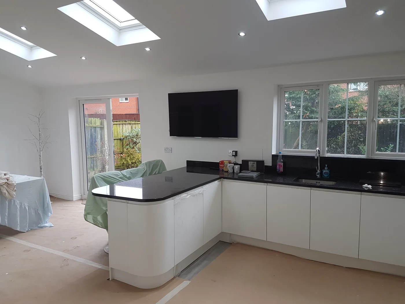 Finished kitchen with a curved white island, black worktops and two roof windows over.