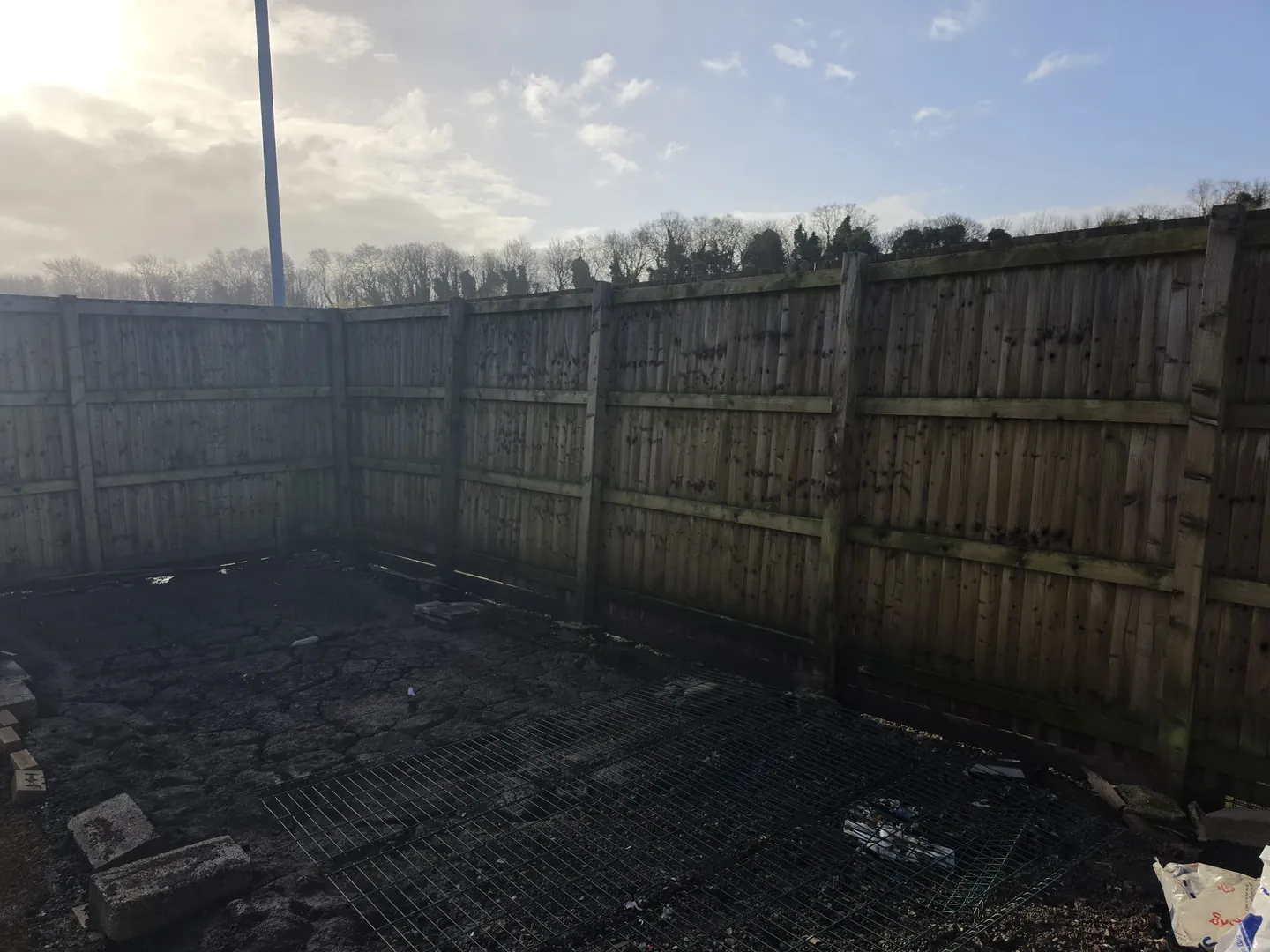 Close-boarded timber boundary fence on concrete posts along a cleared area of the school site.