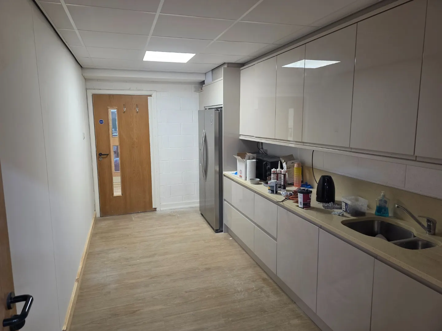 Completed staff kitchen with fitted gloss units, worktop, sink and new flooring.