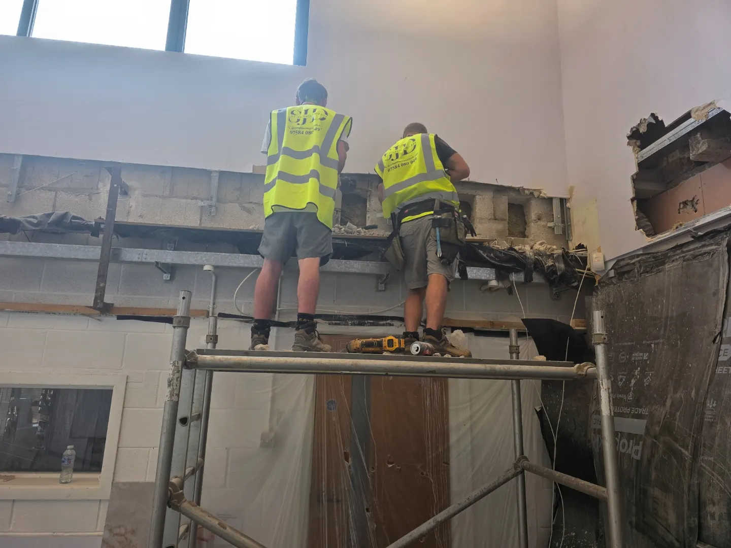 Two SJ Developments operatives in branded hi-vis working from a mobile scaffold tower on the high-level opening.