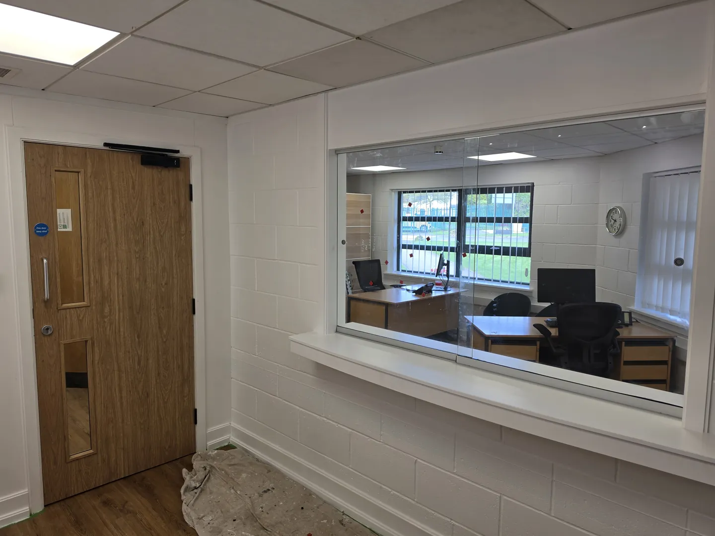 Servery hatch and new oak-faced door with vision panel in a painted blockwork wall.
