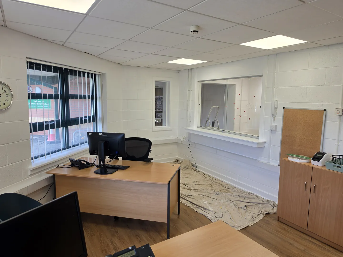 Refurbished school office with desks, new suspended ceiling and LED panels, painted blockwork and wood-effect flooring.