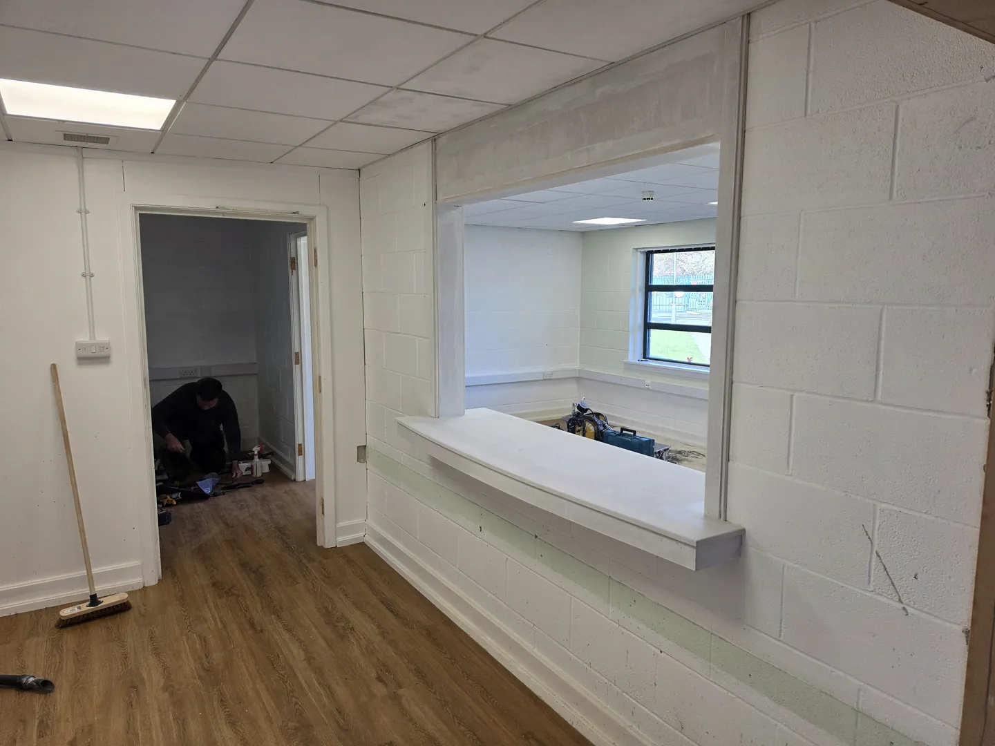 Servery hatch opening formed in blockwork with a new sill, next to a doorway, with LVT flooring laid.