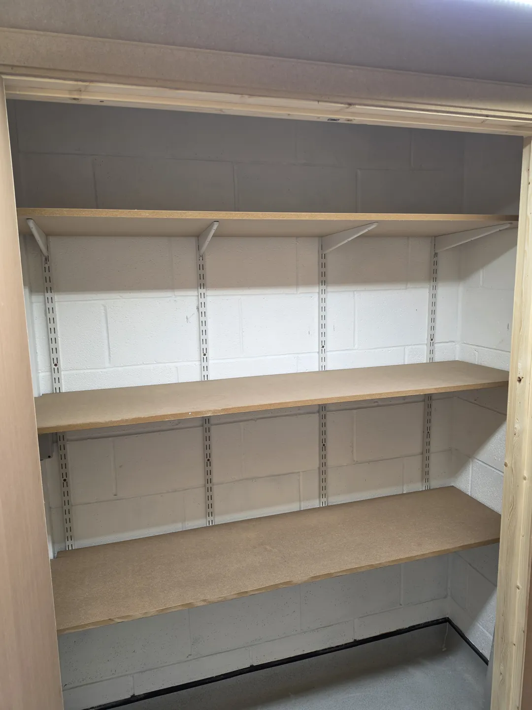 New timber storage shelving on twin-slot brackets fitted in a store room.